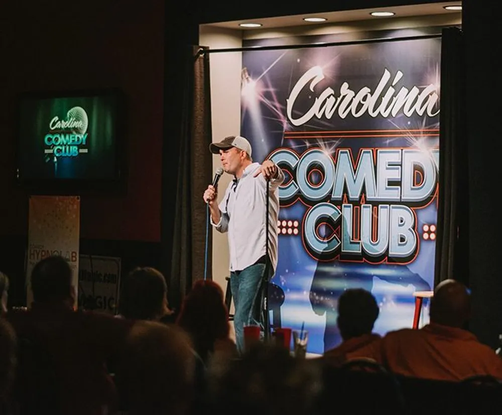 A comedian is performing on stage at the Carolina Comedy Club before an audience