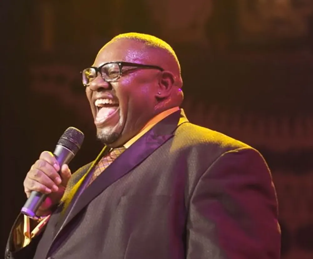 A man is joyfully singing into a microphone on stage