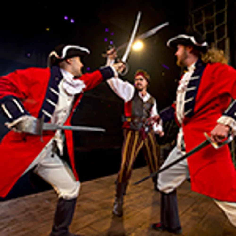 Three performers in period costumes engage in a theatrical sword fight on stage