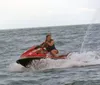 Four people are sitting on red jet skis at a marina on a sunny day