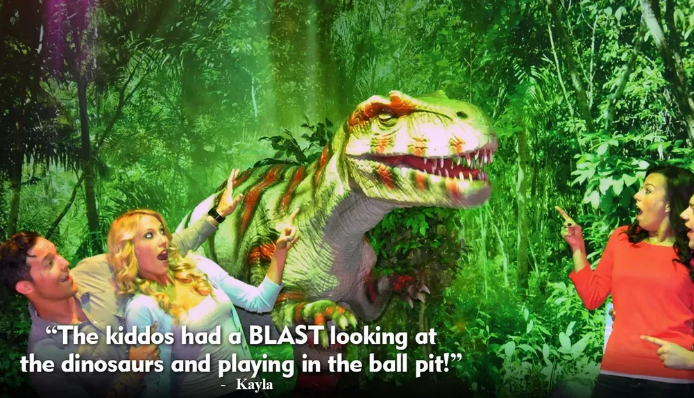 Three people appear to be playfully interacting with a Tyrannosaurus rex in a staged jungle setting