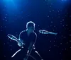 A performer is juggling glowing rings on a stage with a backdrop of bright lights