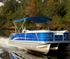 Two individuals are enjoying a ride on a blue and white pontoon boat with a blue sunshade on a calm river surrounded by trees