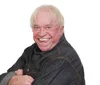 A man in a red cap and a denim shirt is making a surprised or goofy face while pulling his fingers near his temples