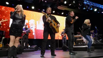 A group of musicians is performing on stage with various instruments, including a guitar, bass, and drums, energizing the audience with their music.