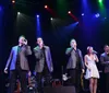 Four performers in red jackets are entertaining an audience on stage during a Frankie Valli tribute show