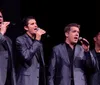 Four performers in red jackets are entertaining an audience on stage during a Frankie Valli tribute show