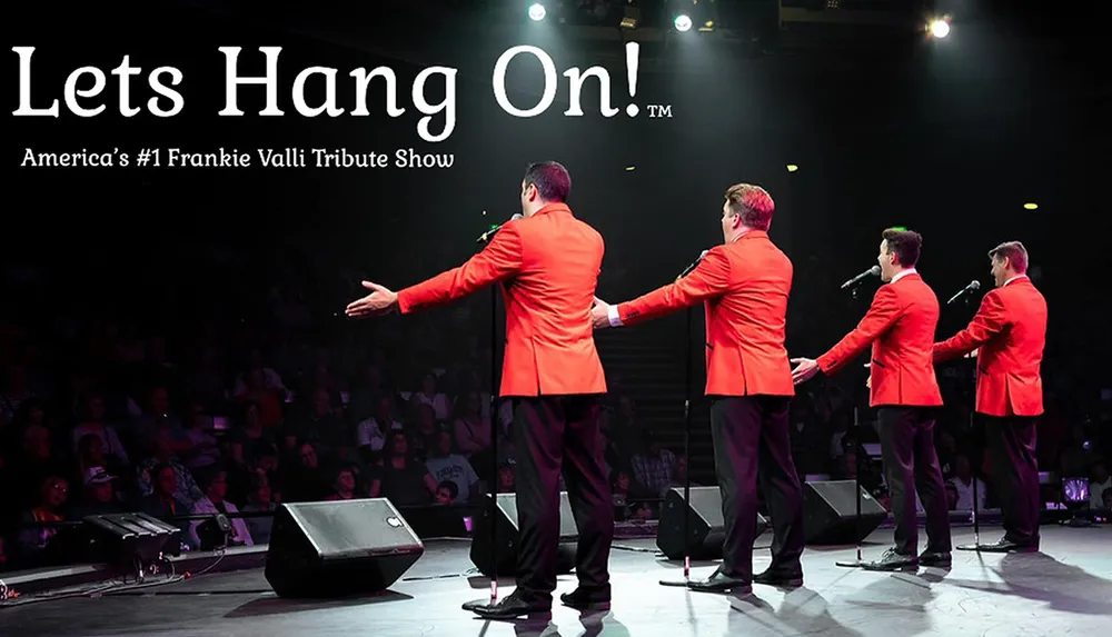 Four performers in red jackets are entertaining an audience on stage during a Frankie Valli tribute show