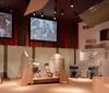 A person appears engrossed in looking at a collection of items on display in a museum exhibit with others around her also viewing the displays