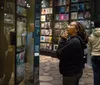 A person appears engrossed in looking at a collection of items on display in a museum exhibit with others around her also viewing the displays