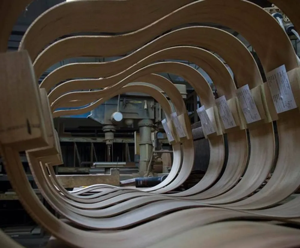 The image shows multiple curved wooden panels in a workshop likely components for furniture or a wooden structure arrayed in a repetitive flowing pattern