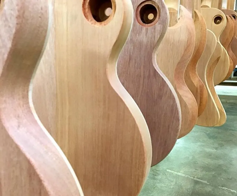 The image shows a close-up of a row of unfinished guitar bodies lined up in a workshop highlighting the craftsmanship involved in their creation