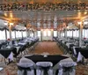 A traditional paddlewheel riverboat is cruising on a river at dusk