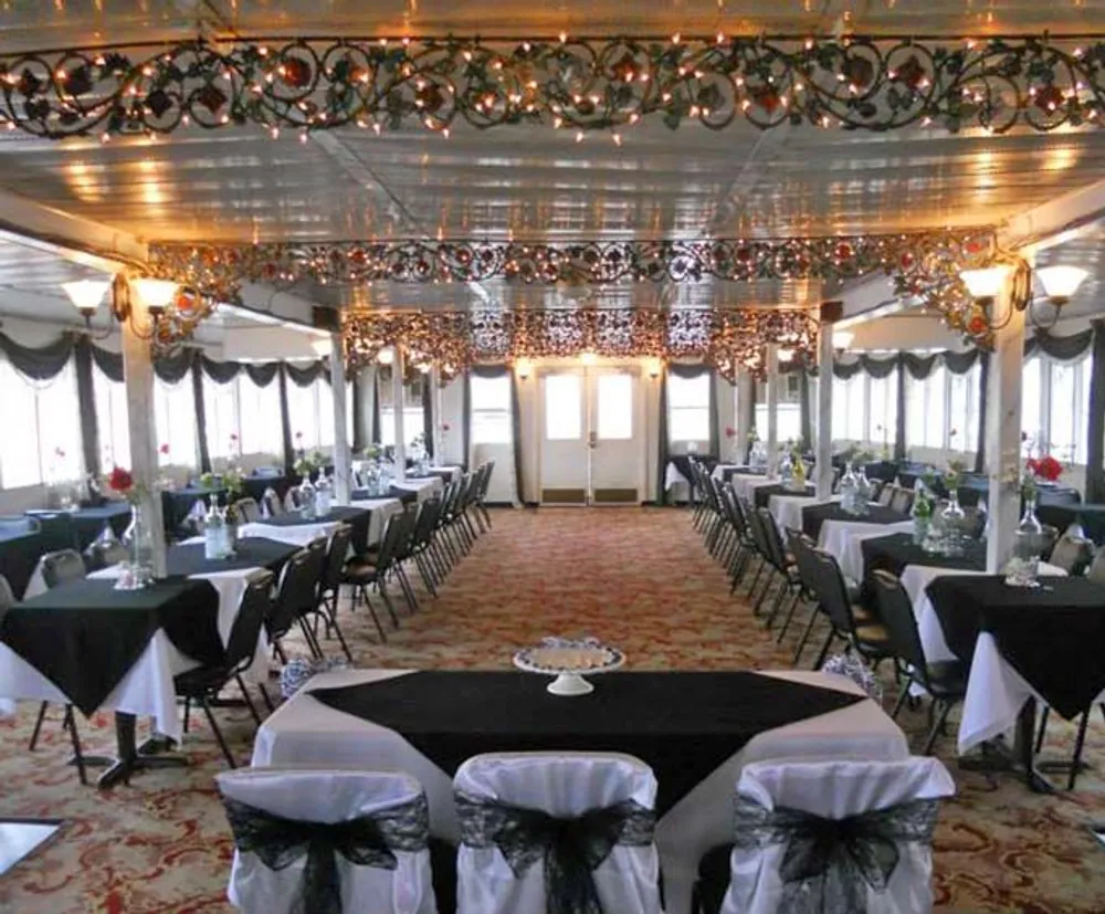 The image shows an elegant dining hall with decorated tables ornate ceiling patterns and festive garlands
