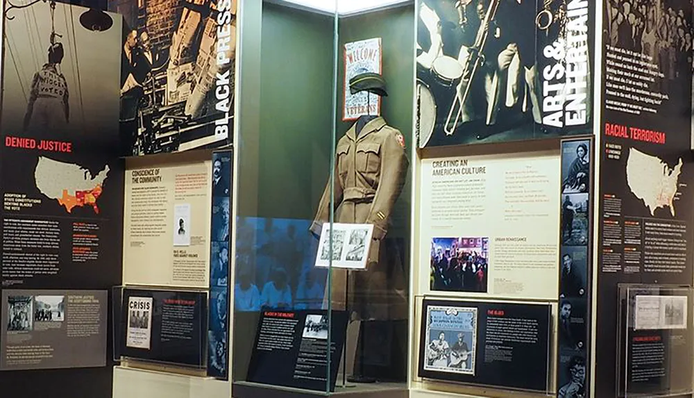 This image features an exhibition display with thematic panels on African American history including topics like the Black Press Arts  Entertainment and Racial Terrorism complemented by a mannequin dressed in a military uniform