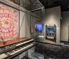 This image shows a music-themed museum exhibit featuring vintage recording equipment several iconic stage costumes on display and large photographs of musicians under a neon sign reading Memphis Recording Service