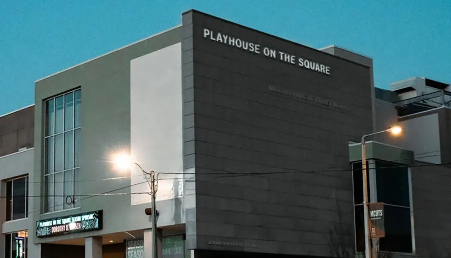The image shows a modern building named Playhouse on the Square with its exterior lights on at dusk.
