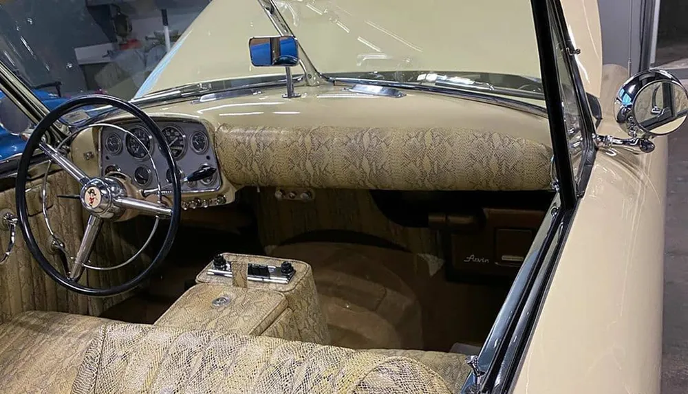 The image showcases the interior of a vintage car featuring a two-tone dashboard with round gauges and a patterned upholstery design