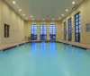 An indoor swimming pool with clear blue water is framed by tall windows and accompanied by a No Diving sign on the wall