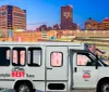 A tour van with Memphis BEST Tours on its side is parked with a backdrop of the Memphis skyline at twilight