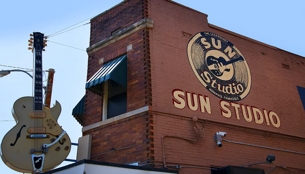 The image displays the exterior of Sun Studio in Memphis Tennessee with its iconic logo mural and a large guitar sign