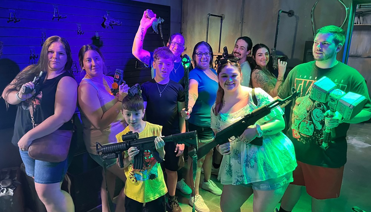 A group of people are posing with toy weapons in a playfully lit room.
